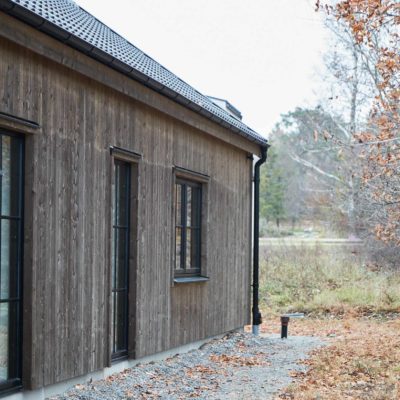 Fasad på arkitektritat enplanshus från Hem1 med stora fönster och träpanel.